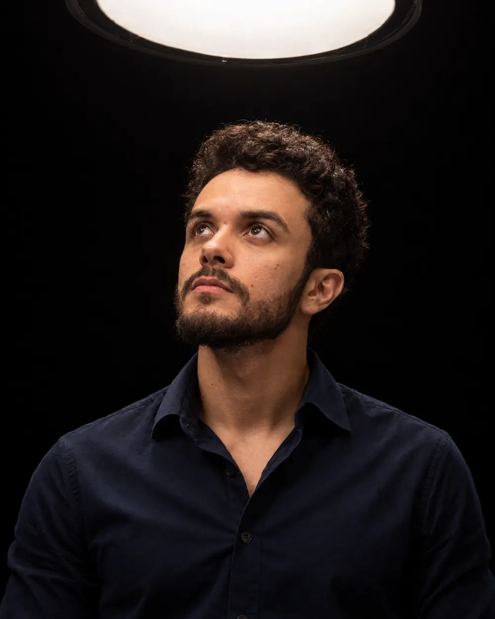 Gustavo Lima olhando para uma luz acima, em estúdio escuro